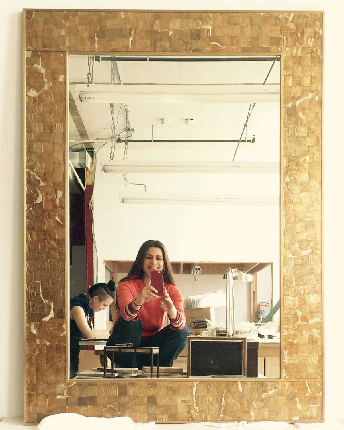 Ariana in her studio with a golden woven mirror
