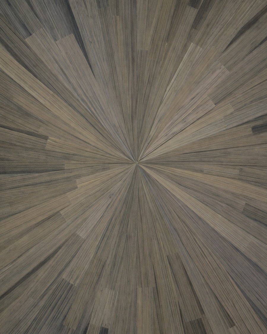 A gray-brown sunburst of straw marquetry radiating from the centre