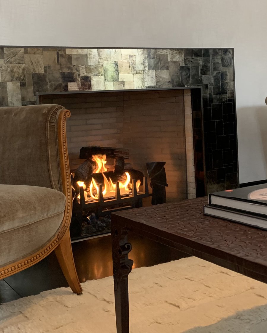 A living-room fireplace surrounded in black and silver mica mosaic, lit by a fire